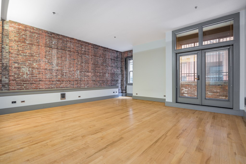 an empty living room with a brick wall and a glass door