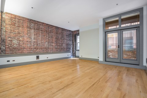 an empty living room with a brick wall and a glass door