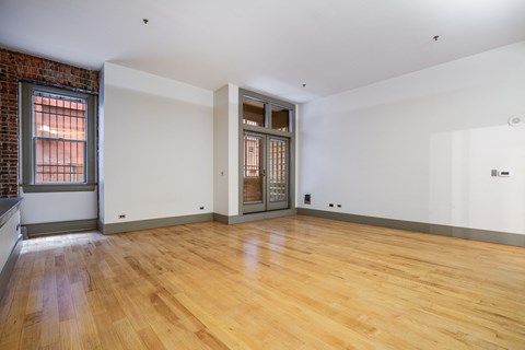 a living room with white walls and wood floors and a glass door