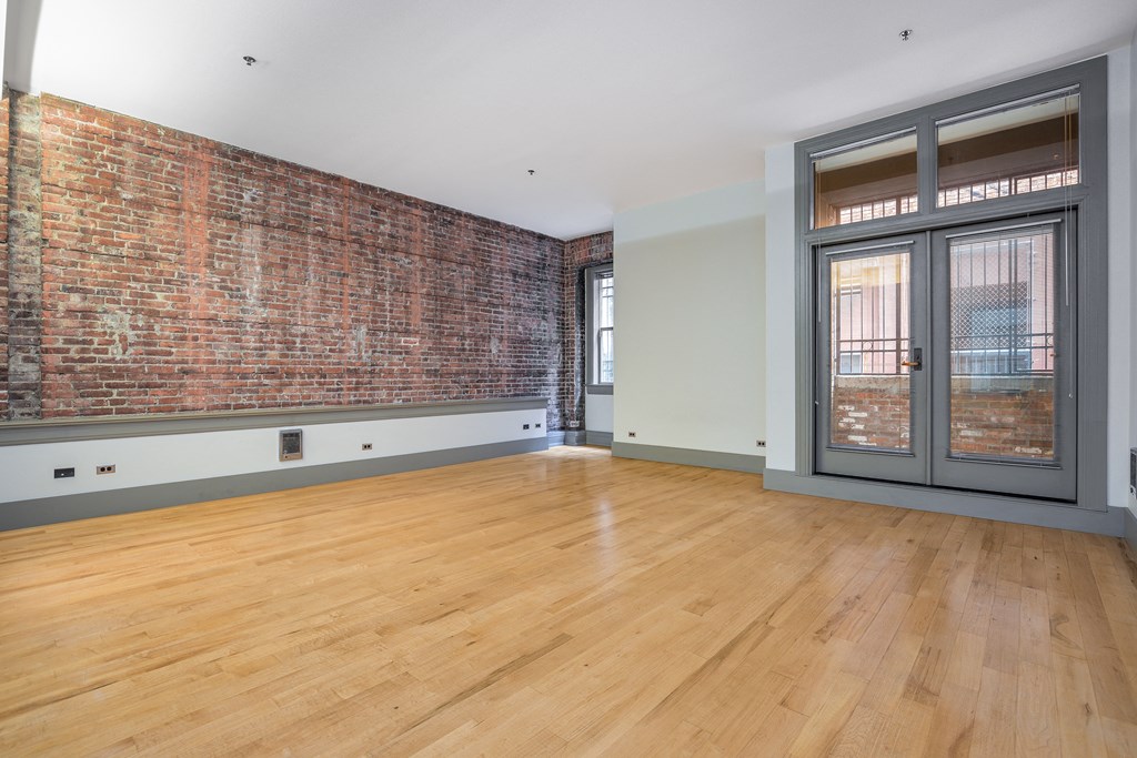 an empty living room with a brick wall and a glass door