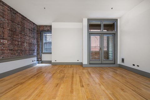an empty living room with a brick wall and a glass door