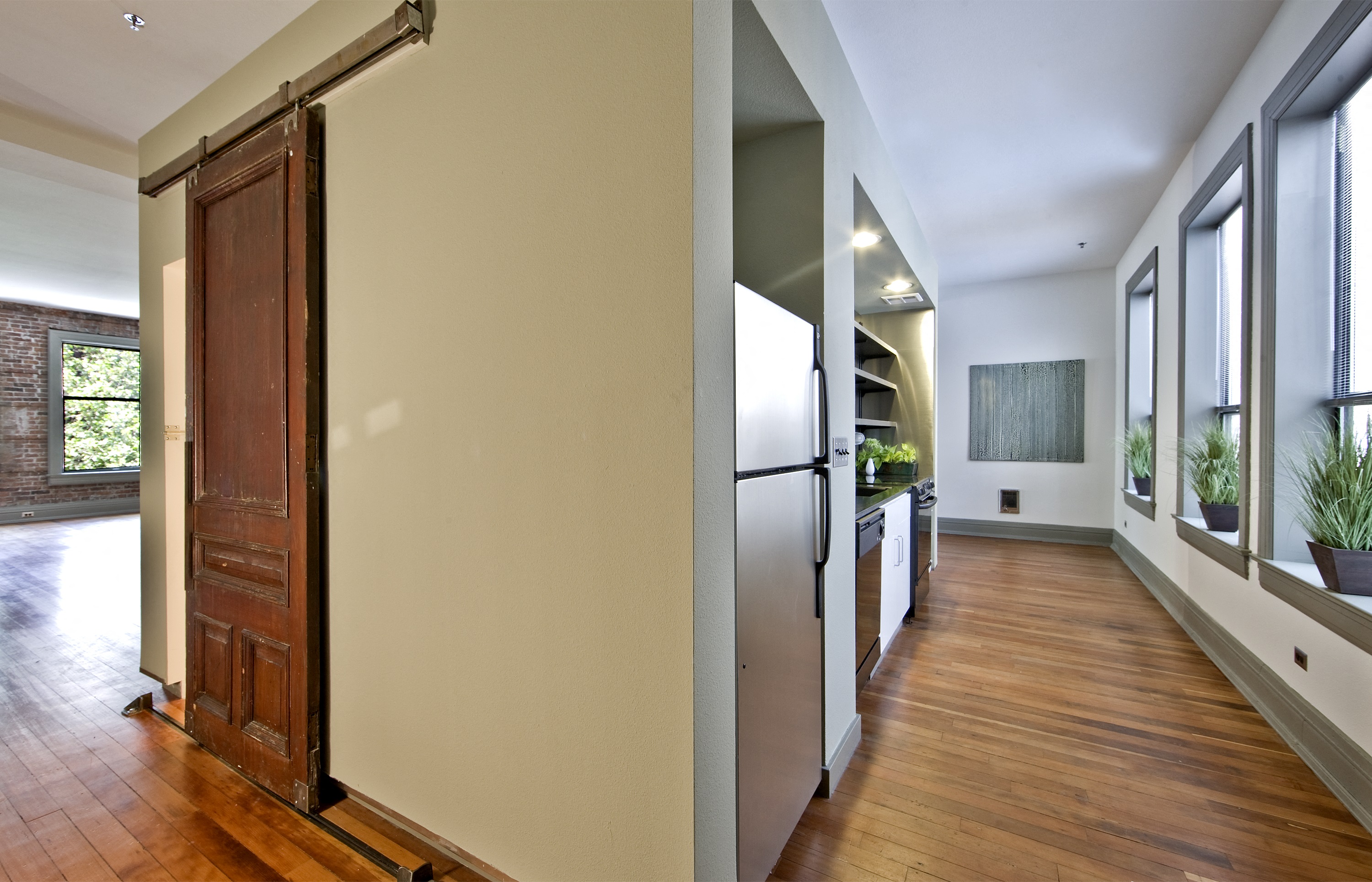 a kitchen and living room with a wood floor and white walls and a refrigerator