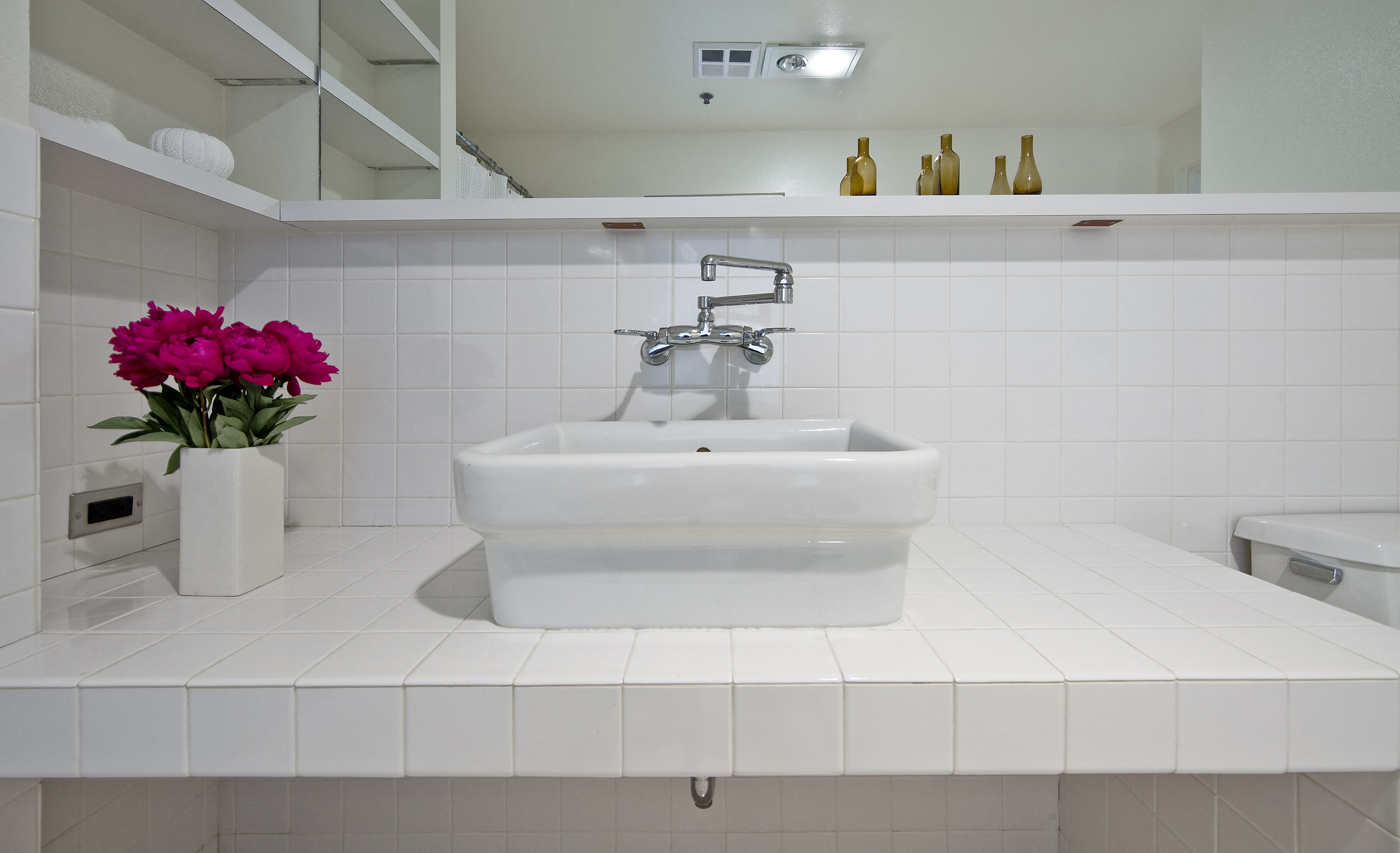 a white bathroom with a sink and a vase of flowers