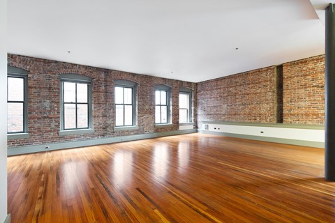 an empty room with brick walls and wood floors