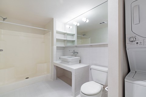 a white bathroom with a sink toilet and a washer and dryer