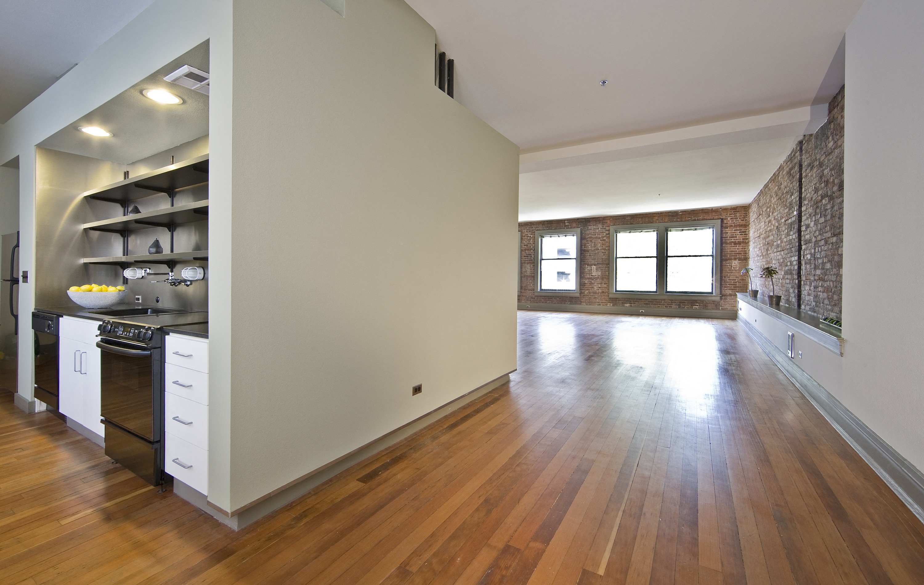 an open kitchen and living room with wood floors and white walls