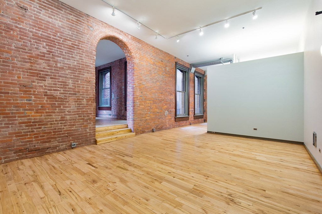 a room with exposed brick and a white wall and wooden floors