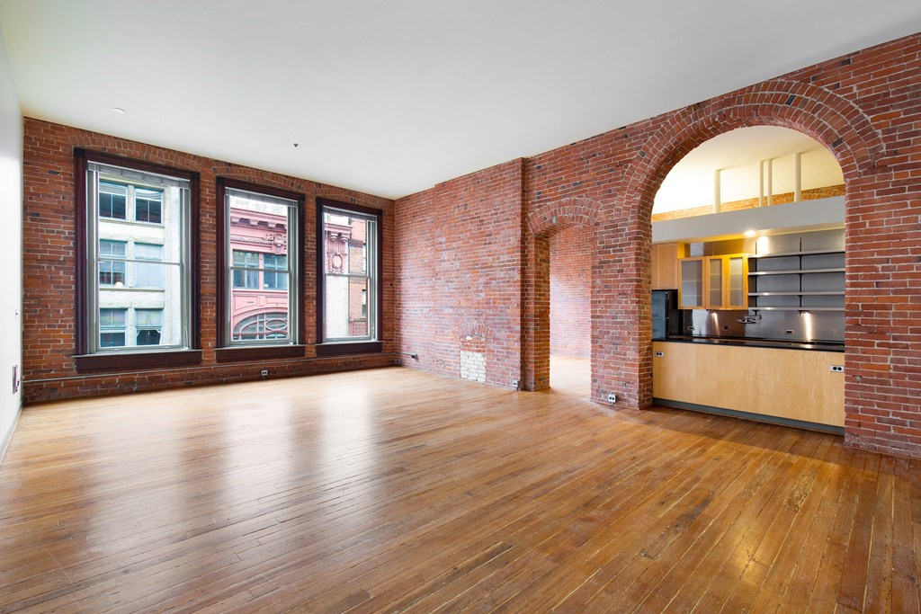 an empty living room with brick walls and wood floors