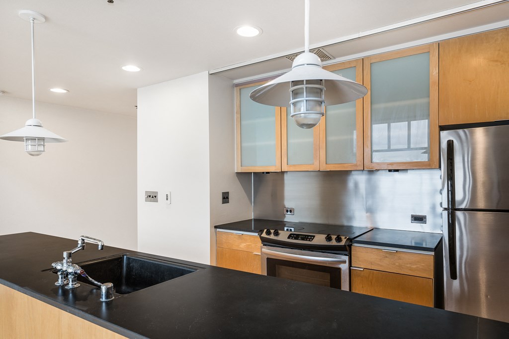 a kitchen with a black counter top and a stainless steel refrigerator