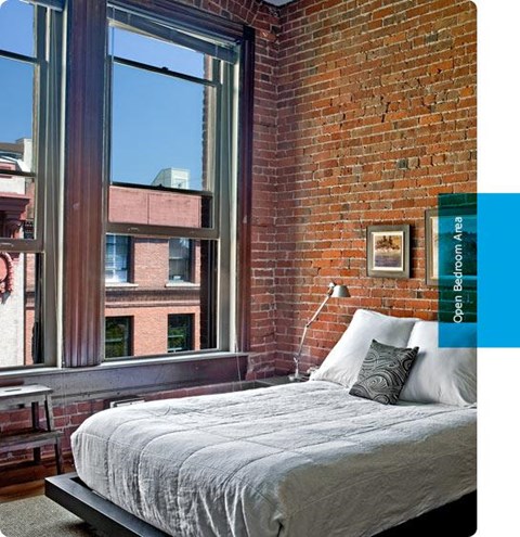 a bedroom with a bed and a brick wall