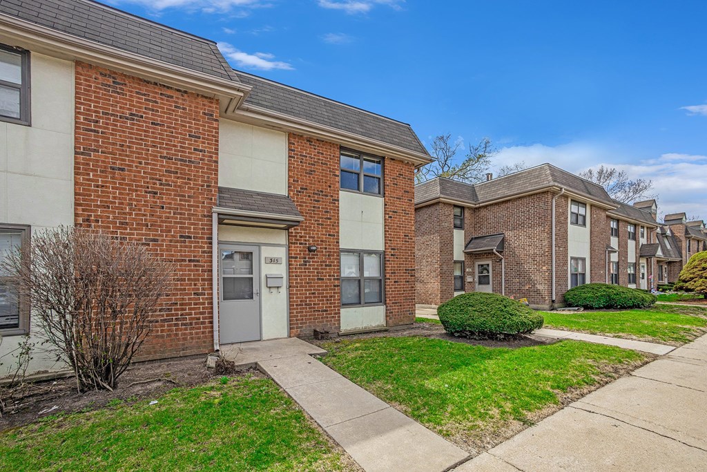A row of red brick houses with green lawns in front.