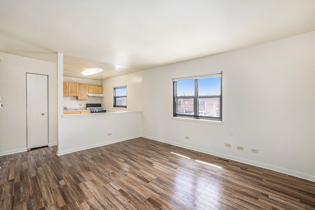 A room with wooden flooring and a window overlooking a building.