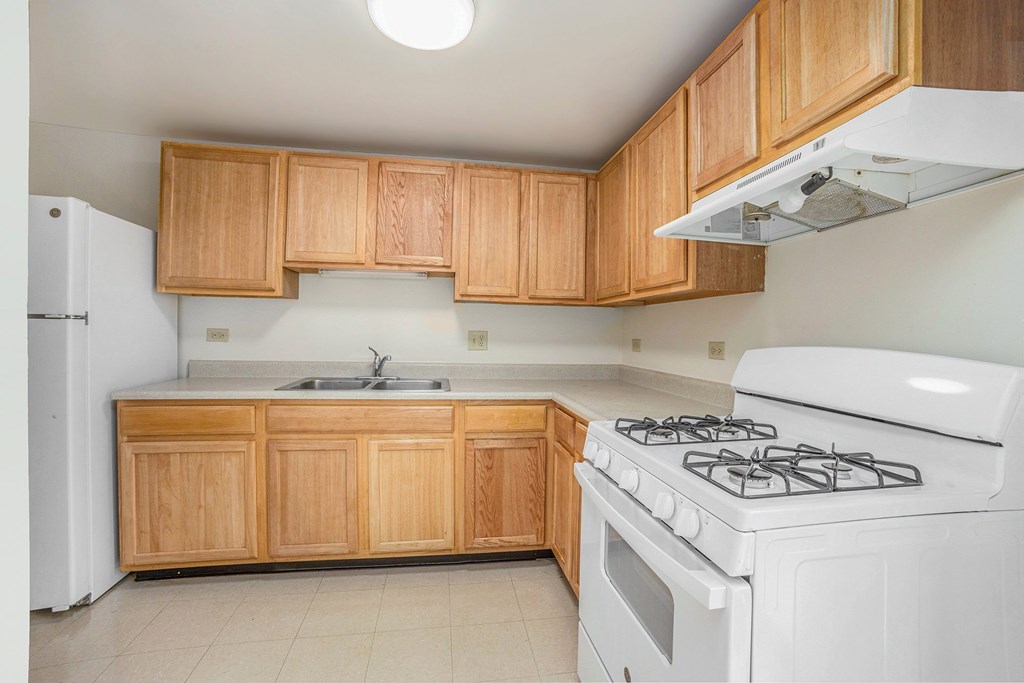 A kitchen with a white stove and wooden cabinets.