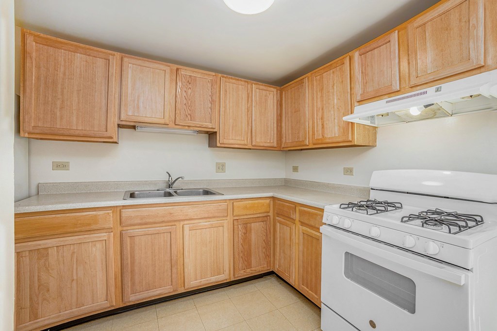 A kitchen with wooden cabinets and a white stove.
