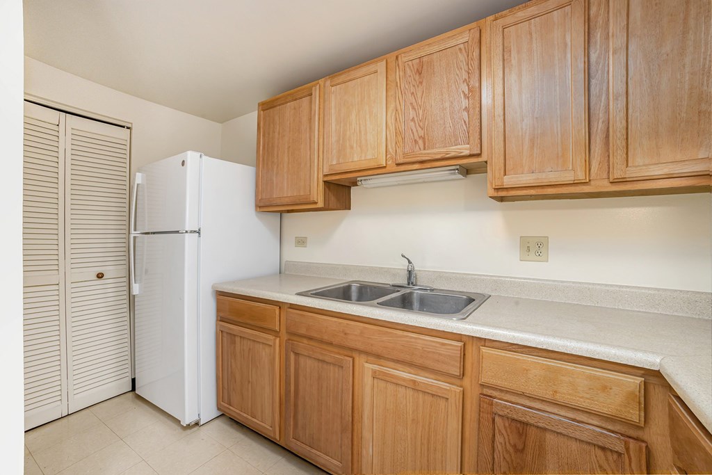A kitchen with wooden cabinets and a white refrigerator.