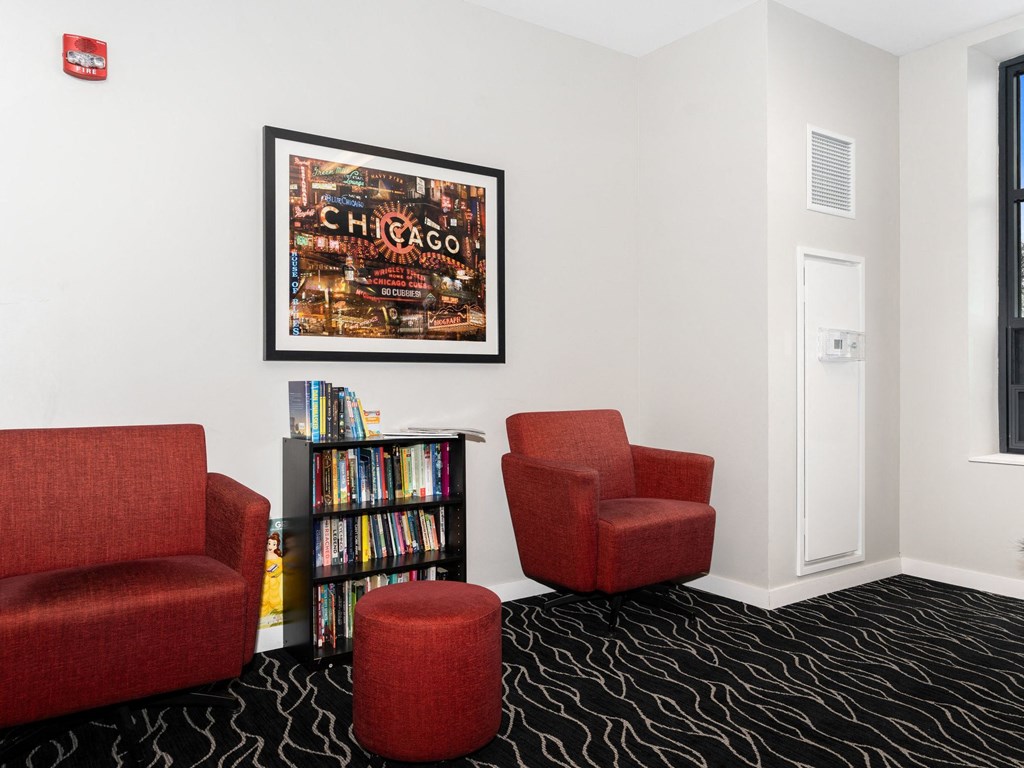a room with three red chairs and a bookshelf filled with books