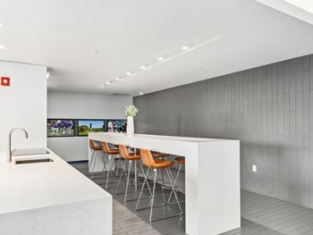 a kitchen with white marble countertops and a bar with orange chairs at One 333, Chicago, Illinois, 60605