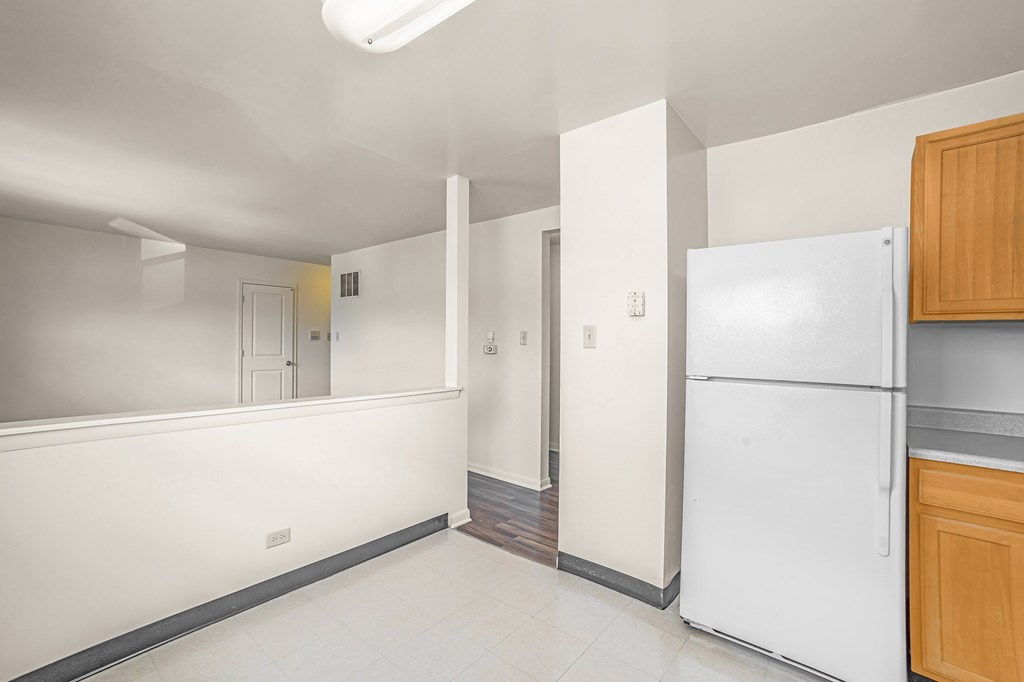 A white refrigerator sits in a kitchen next to a wooden cabinet.