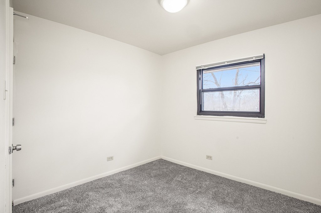 A room with a window and carpeted floor.