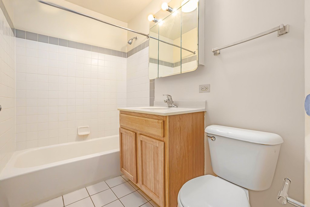 A white toilet sits next to a wooden cabinet in a bathroom.