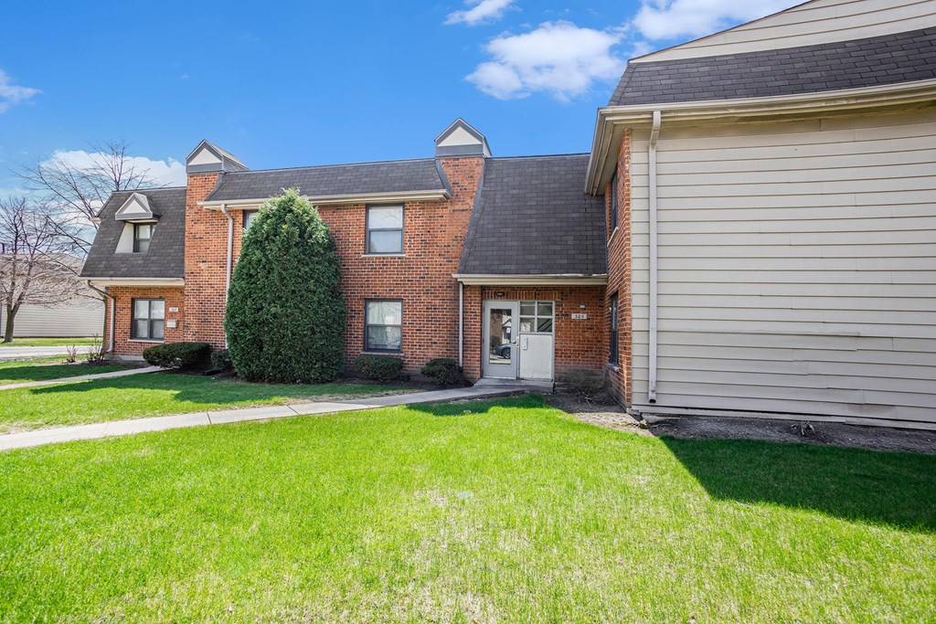 A house with a white door and a green lawn in front.