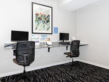 a office with two chairs and a desk with computers