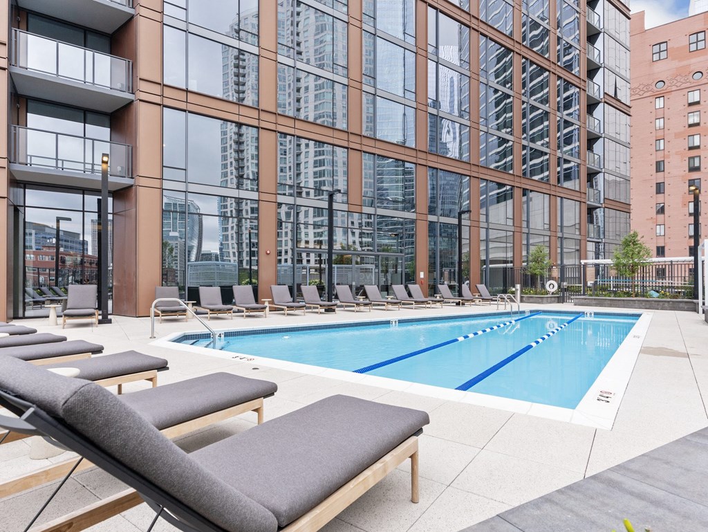 a swimming pool with lounge chairs in front of a tall building at Cassidy on Canal, Chicago, IL, 60606