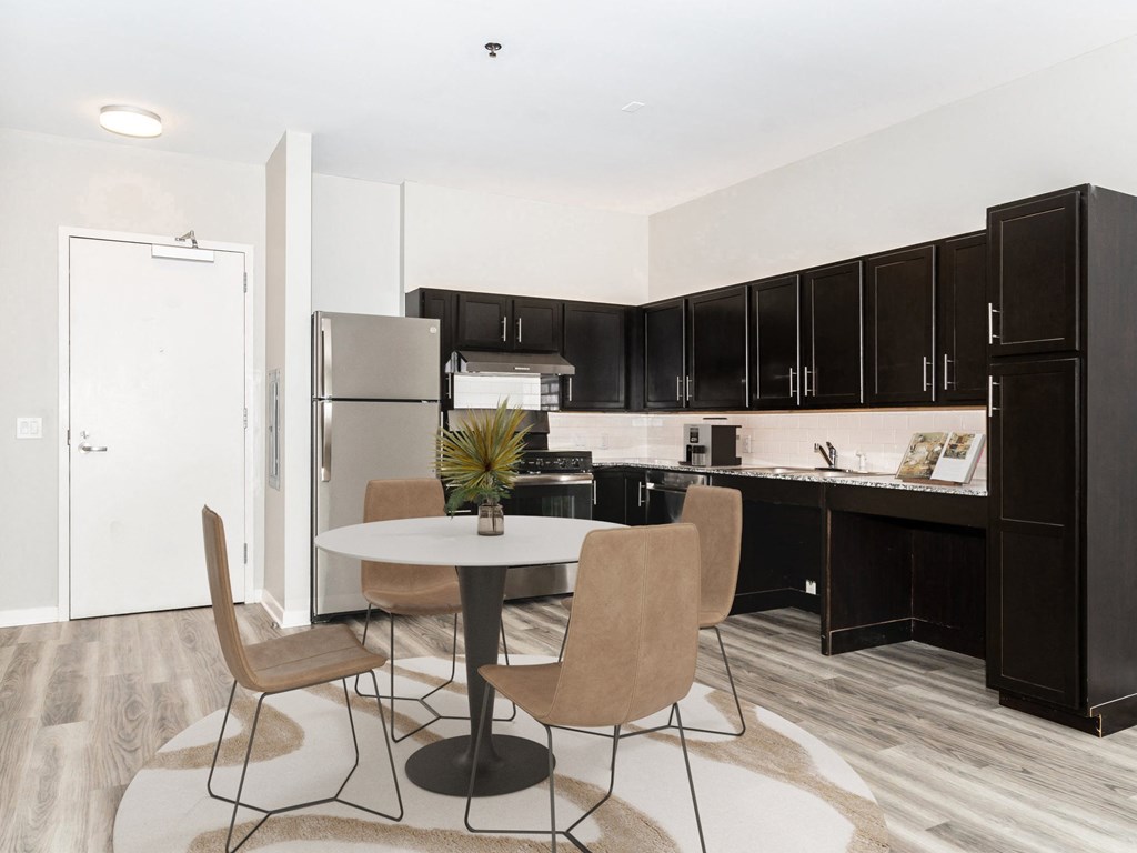a kitchen and dining area with black cabinets and a refrigerator