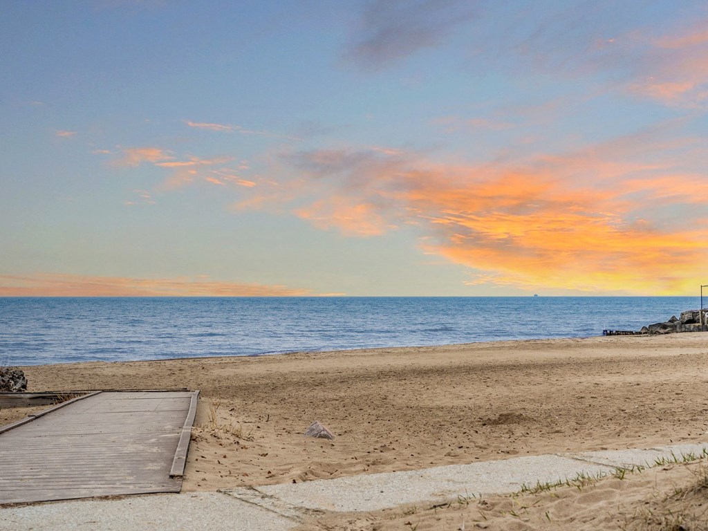 a sunset over the beach with a wooden dock on the beach