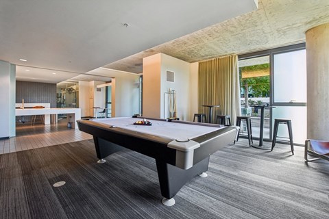 A pool table is in the middle of a room with a wooden floor.