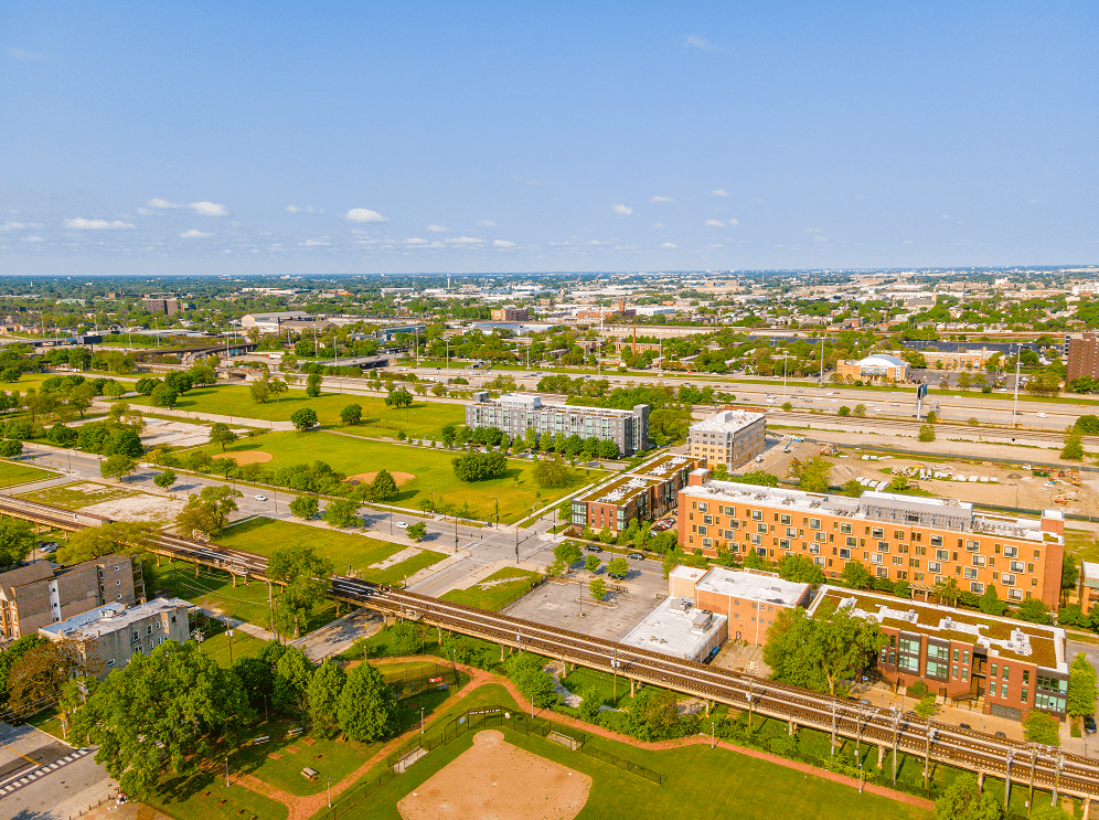 an aerial view of a city with a train track in the foreground and buildings in the background