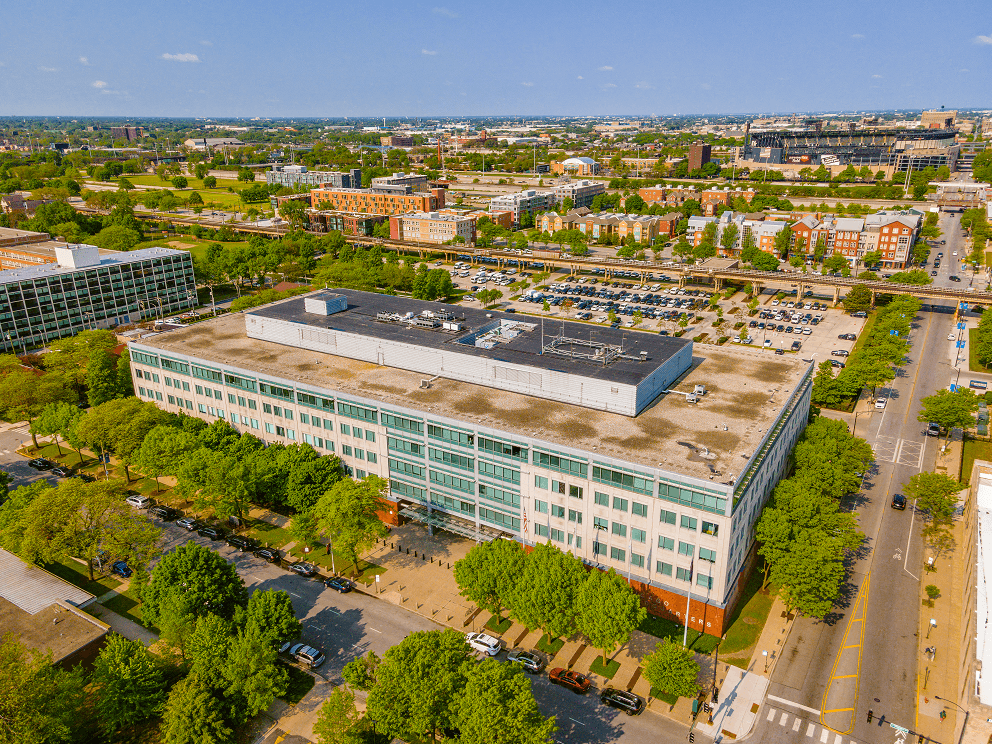 an aerial view of a large building with trees in front of it and a city in the