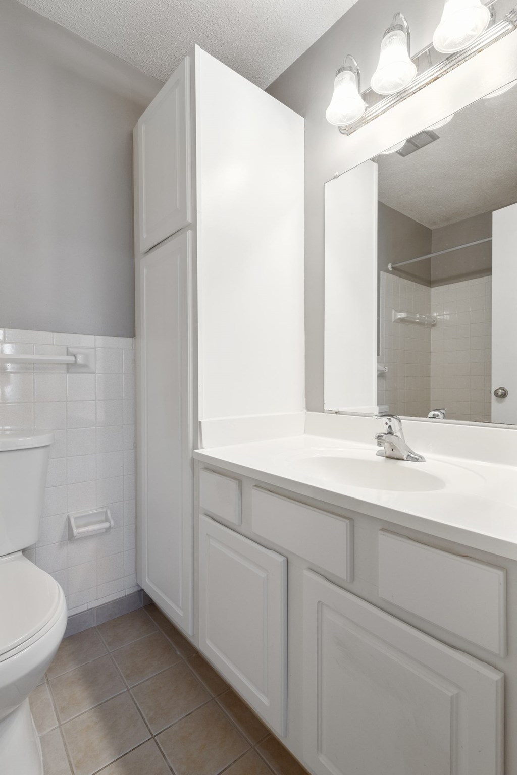 A white bathroom with a toilet, sink, and mirror.