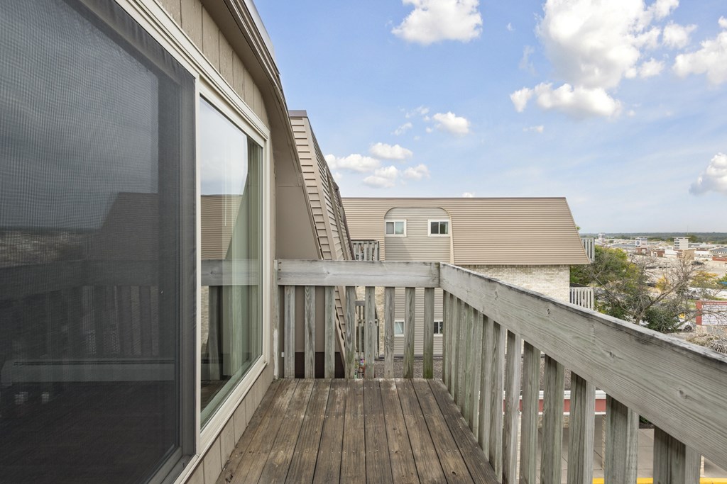 A balcony with a wooden floor and a glass door.