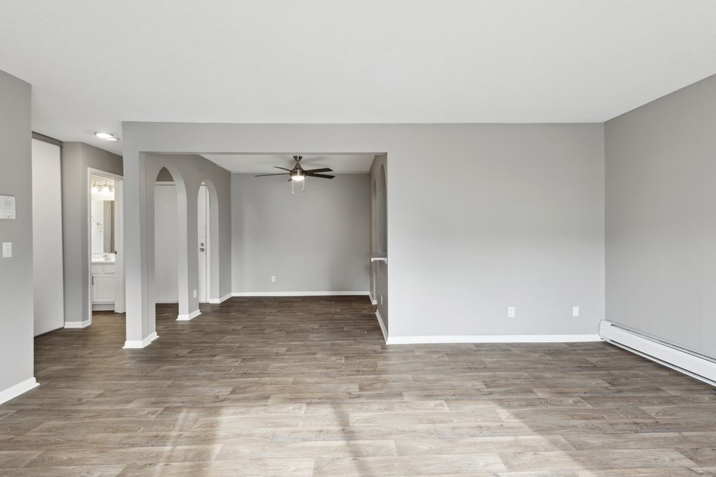A spacious room with a ceiling fan and light wood flooring.