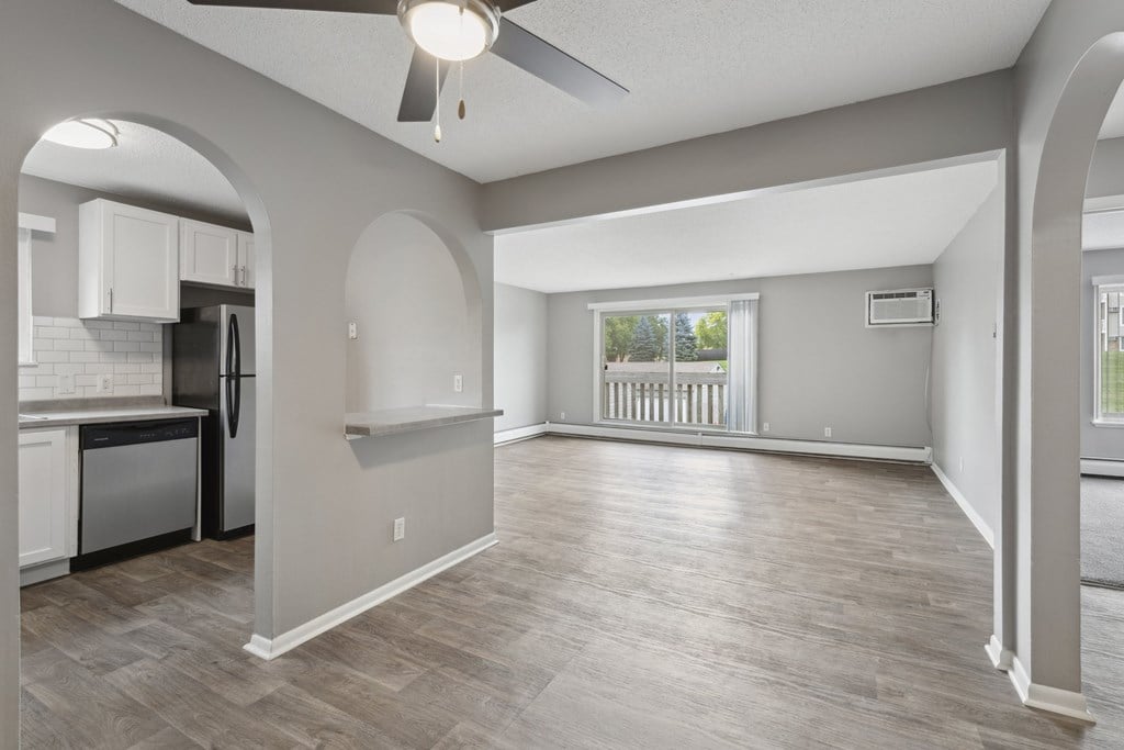 A spacious kitchen and living room with a ceiling fan and light fixture.