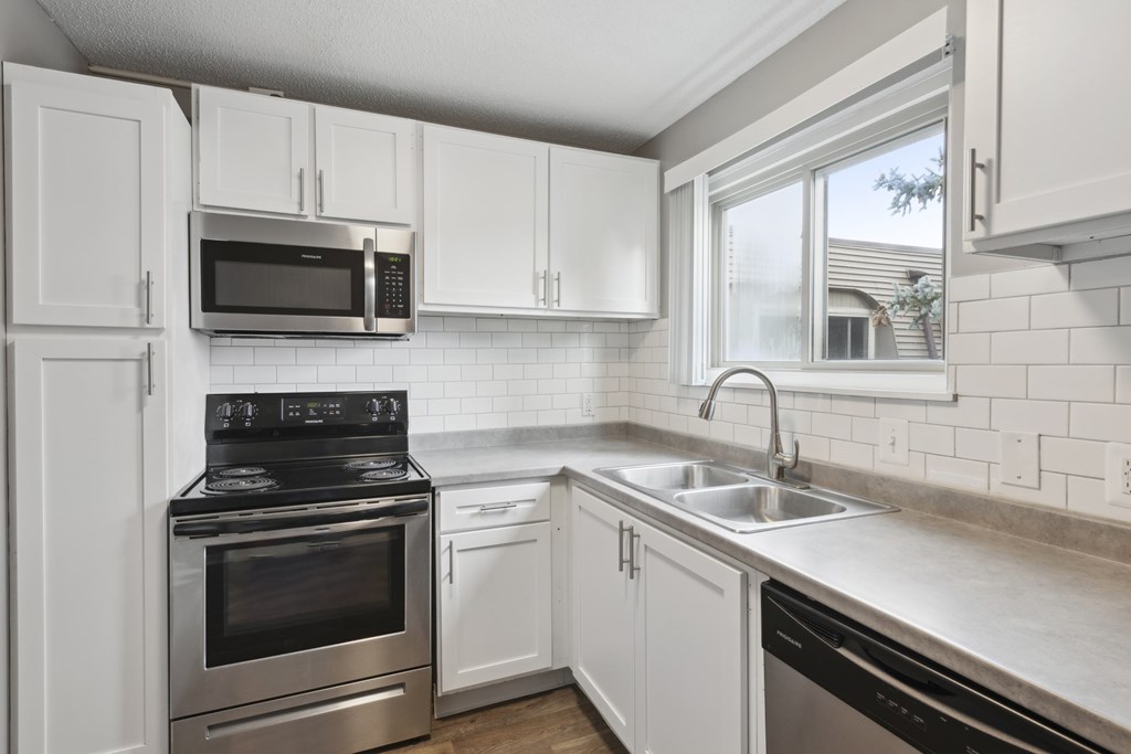 A modern kitchen with white cabinets and stainless steel appliances.