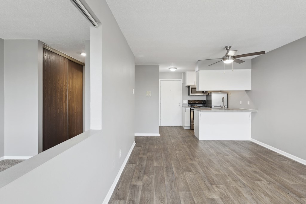 A room with a ceiling fan and a kitchenette.
