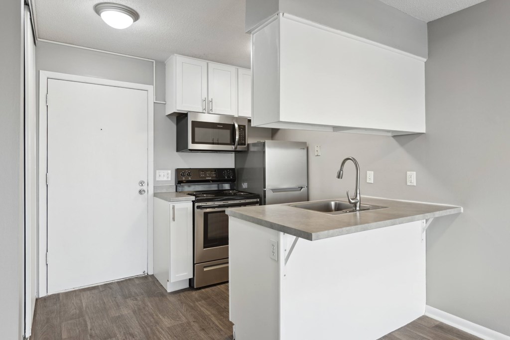 A kitchen with white cabinets and a wooden floor.