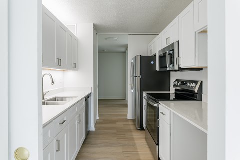 A kitchen with white cabinets and black appliances.