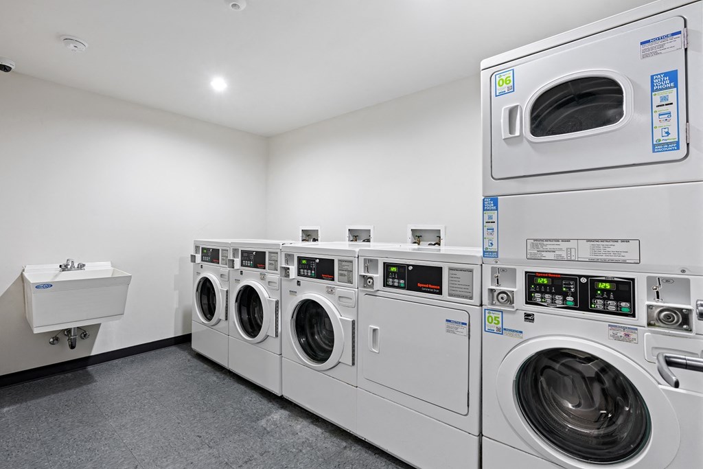 a laundry room with a row of washing machines and a sink