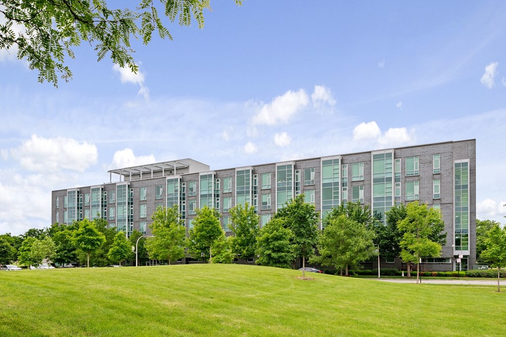 a large building with green grass and trees in front of it