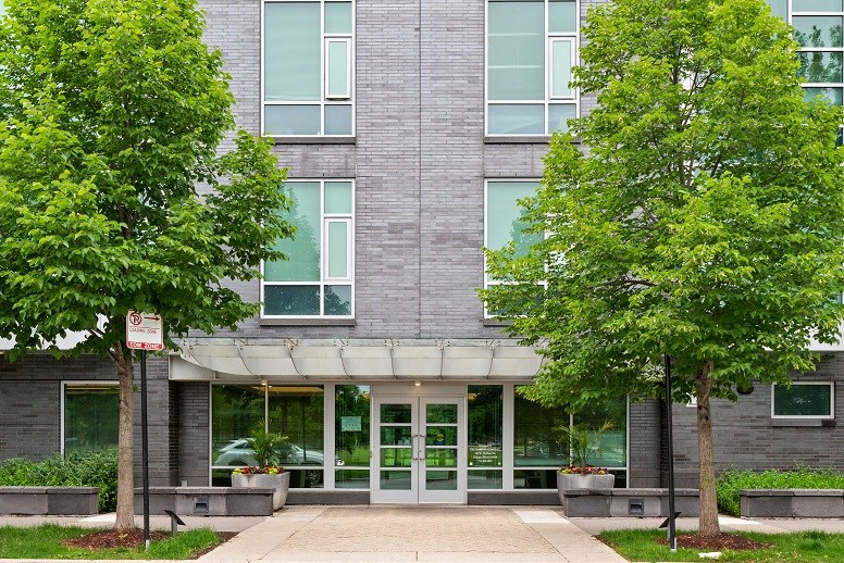 the front of a building with trees and a sidewalk