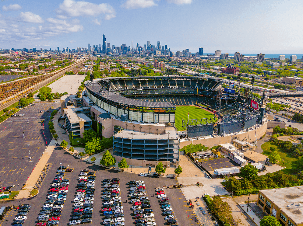 A large stadium with a parking lot in front of it.