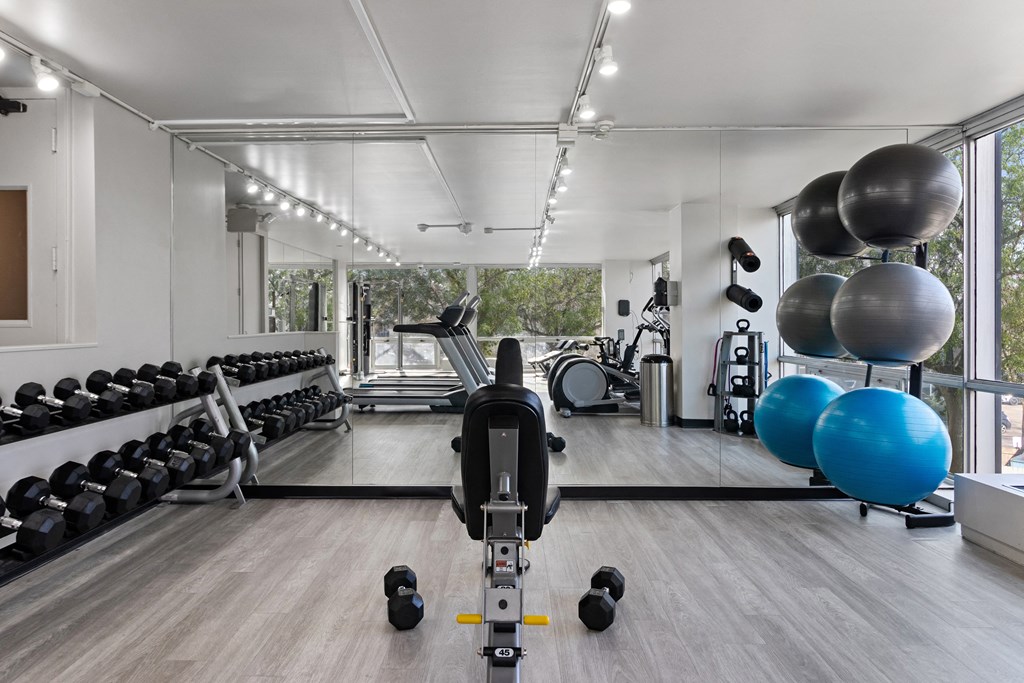 a gym with cardio equipment and weights on the floor and a large window at The Pavilion, Michigan, 48207