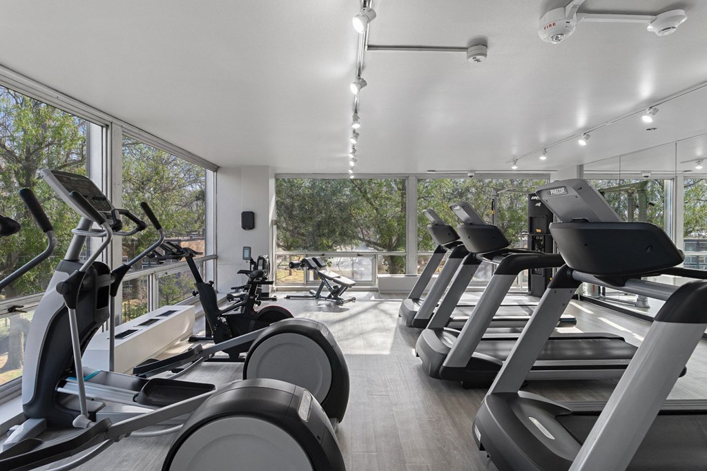 a gym with treadmills and other cardio equipment in a building with large windows at The Pavilion, Michigan, 48207