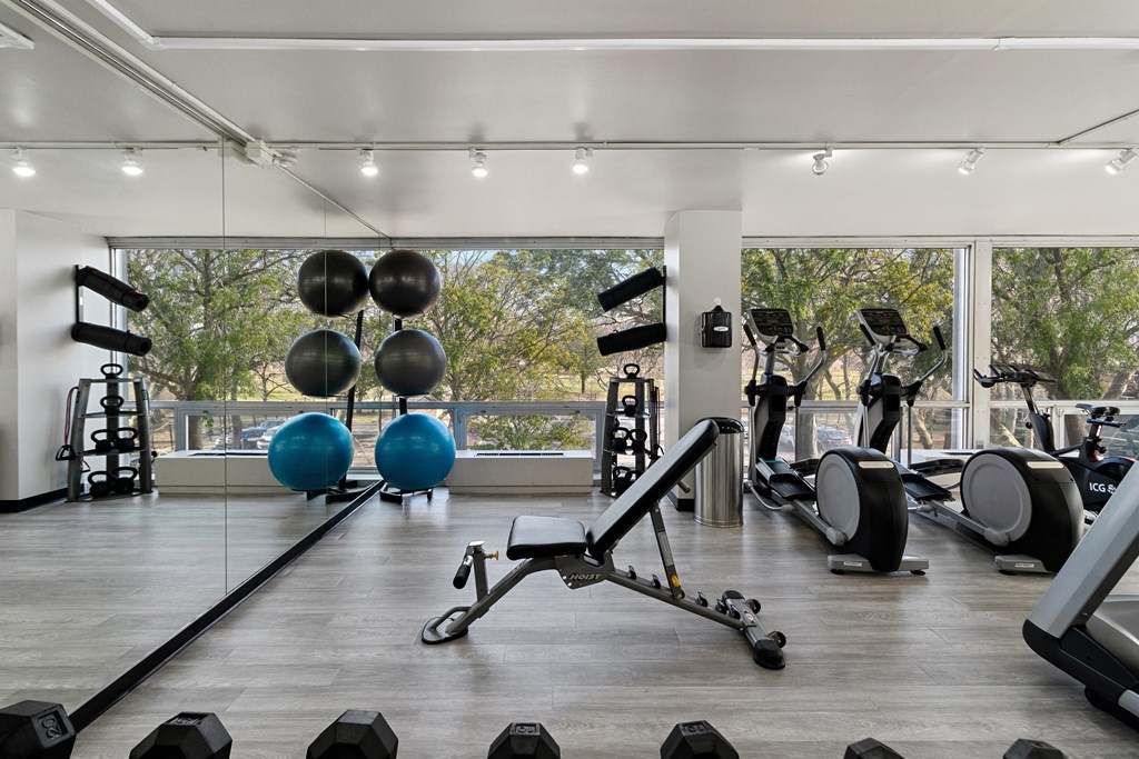 a gym with weights and cardio equipment and a large window at The Pavilion, Detroit