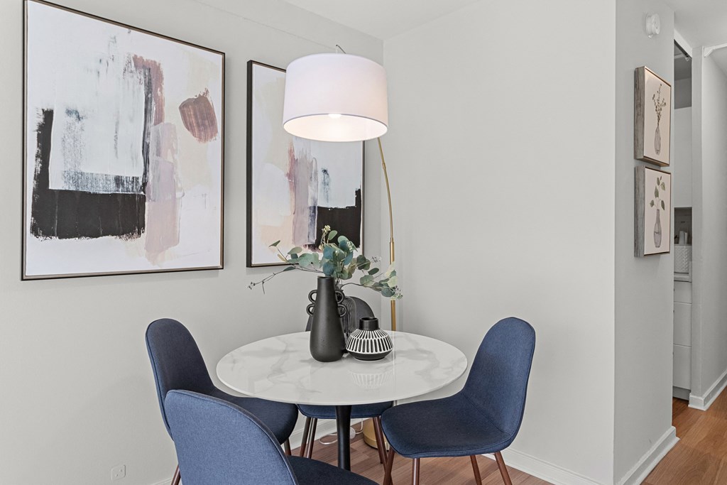 a dining room with blue chairs and a white table with a lamp and paintings on at The Pavilion, Detroit, Michigan