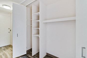 a walk in closet with white walls and shelves