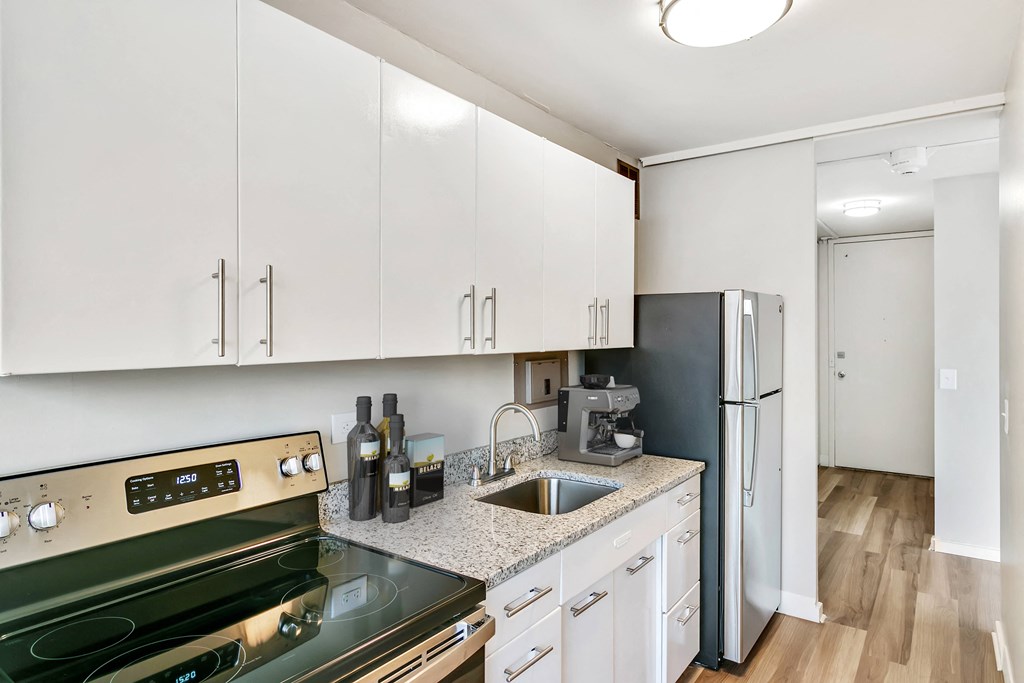 a kitchen with white cabinets and stainless steel appliances at The Pavilion, Detroit, MI